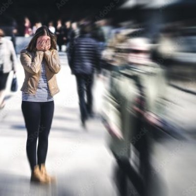 Woman standing with head in hands in middle of busy city. Adobe